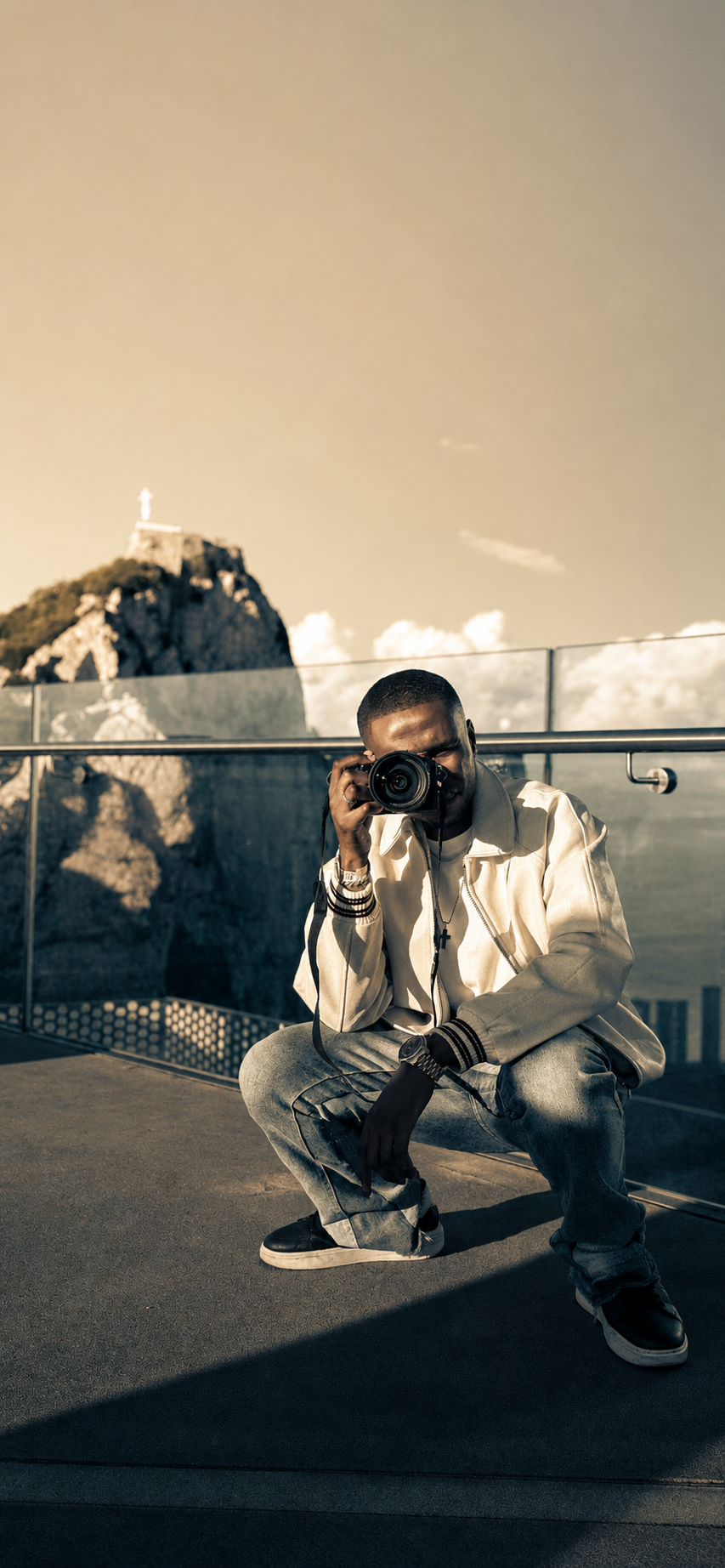 Photographer crouching with camera on rooftop, black and white portrait